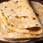 Close-up homemade Indian chapati flatbread that have been brushed with ghee featuring a title overlay.