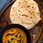 Overhead Indian meal of Ceylon chicken curry with homemade chapati flatbreads.