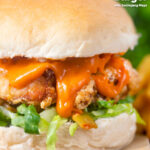 Korean-influenced crispy fried chicken burger with gochujang mayo and kimchi featuring a title overlay.