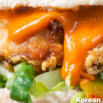 Close-up Korean-influenced crispy fried chicken burger with gochujang mayo featuring a title overlay.