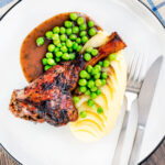 Overhead oven cooked minted lamb shanks served with peas, mashed potato and red wine gravy.