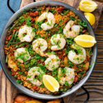 Overhead prawn and chorizo paella served in a paella pan with lemon and parsley.