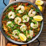 Overhead prawn and chorizo paella served in a paella pan with lemon and parsley.