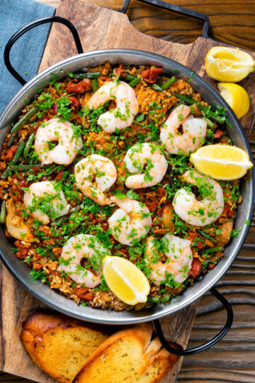 Overhead prawn and chorizo paella served in a paella pan with lemon and parsley.