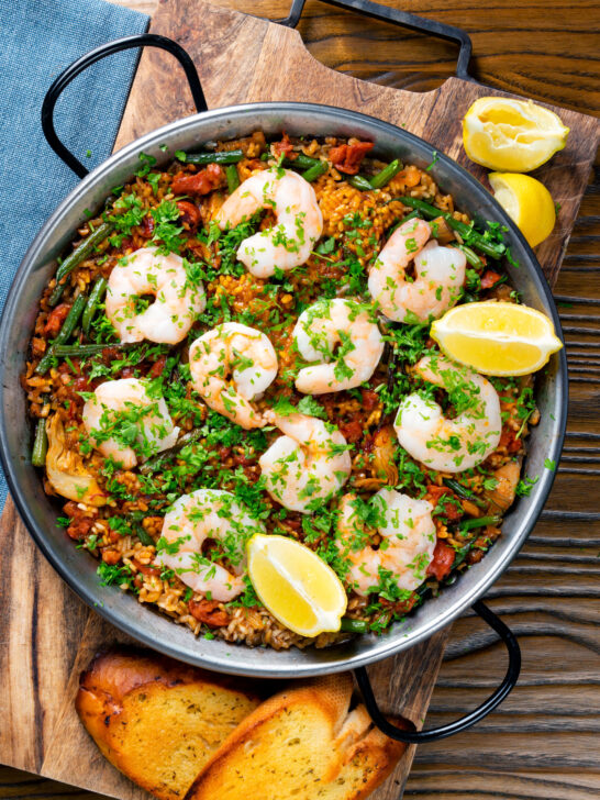 Overhead prawn and chorizo paella served in a paella pan with lemon and parsley.
