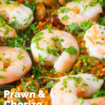 Close-up prawn and chorizo paella served in a paella pan with lemon and parsley featuring a title overlay.