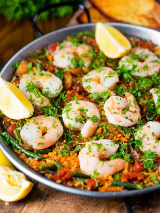 Prawn and chorizo paella served in a paella pan with lemon and parsley.