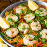 Prawn and chorizo paella served in a paella pan with lemon and parsley featuring a title overlay.