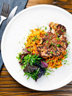 Overhead oven roasted cauliflower steak served with giant couscous salad.