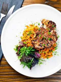 Overhead oven roasted cauliflower steak served with giant couscous salad.