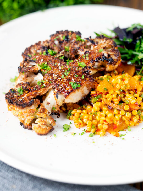 Oven roasted and glazed cauliflower steak served with giant couscous salad.