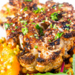 Close-up oven roasted cauliflower steak served with giant couscous salad.