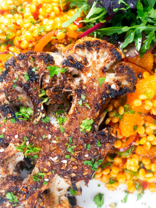 Overhead close-up oven roasted cauliflower steak served with giant couscous salad.