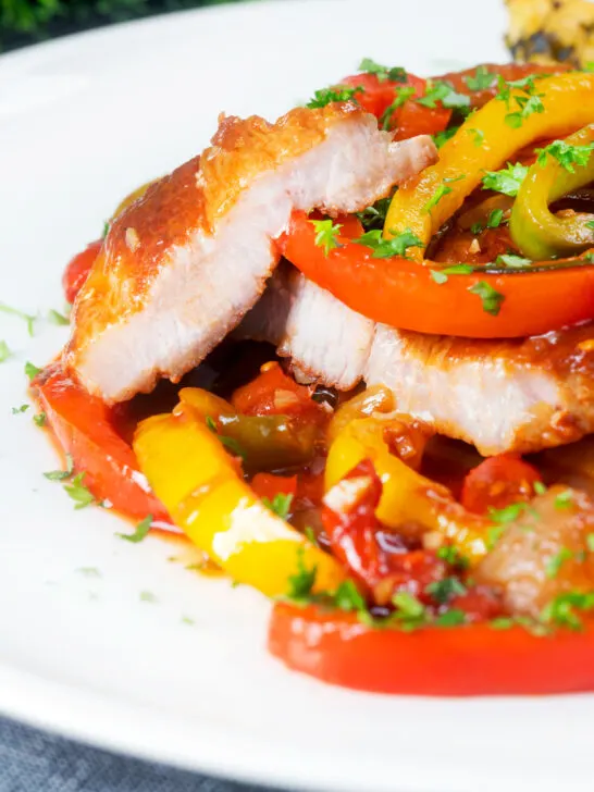 Slow cooker pork chops with peppers, tomatoes cut open to show succulent texture.