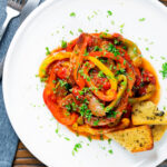 Overhead slow cooker pork chops with peppers, tomatoes and Worcestershire sauce.