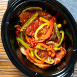 Overhead Crock Pot pork chops with peppers, tomatoes and Worcestershire sauce.