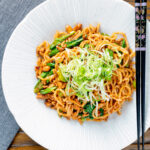 Overhead dan dan noodles, a spicy pork mince stir fry with peanuts and chilli with spring onions.