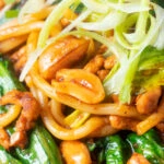Close-up dan dan noodles, a spicy pork mince stir fry with peanuts with spring onions.