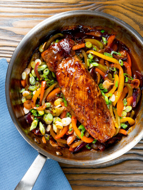 Overhead roasted sweet and sour pork fillet with peppers in a pan.