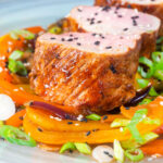 Close-up roasted sweet and sour pork tenderloin with mixed peppers.