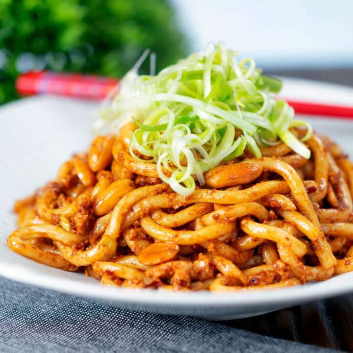 Crumbled tofu noodle stir fry with peanuts and dan dan style sauce with shredded spring onions.