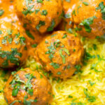 Overhead close-up venison meatballs in an Indian-style yoghurt-based curry sauce with pilau rice.