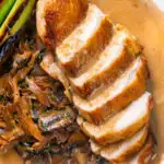 Overhead close-up sliced chicken breast forestiere or mushrooms in a creamy sauce featuring a title overlay.