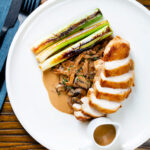 Overhead sliced chicken breast forestiere or mushrooms in a creamy brandy sauce.