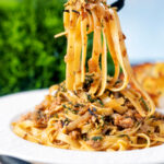 Chicken and sage pasta with caramelised onions and sage crumb being picked up with a fork.