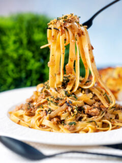 Chicken and sage pasta with caramelised onions and sage crumb being picked up with a fork.