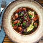 Overhead coq au vin with carrots, mushrooms bacon and shallots served with mashed potato.