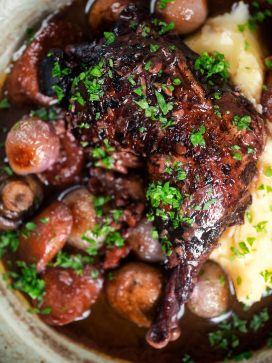 Overhead close up coq au vin, chicken legs braised in red wine with vegetables and bacon.