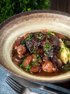 French coq au vin with carrots, mushrooms bacon and shallots served with mashed potato.