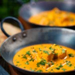 Creamy Indian shahi paneer curry served with naan bread in an iron karai.