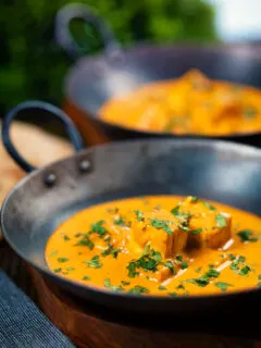 Creamy Indian shahi paneer curry served with naan bread in an iron karai.