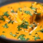 Close-up Indian shahi paneer curry in a creamy sauce served with fresh coriander.