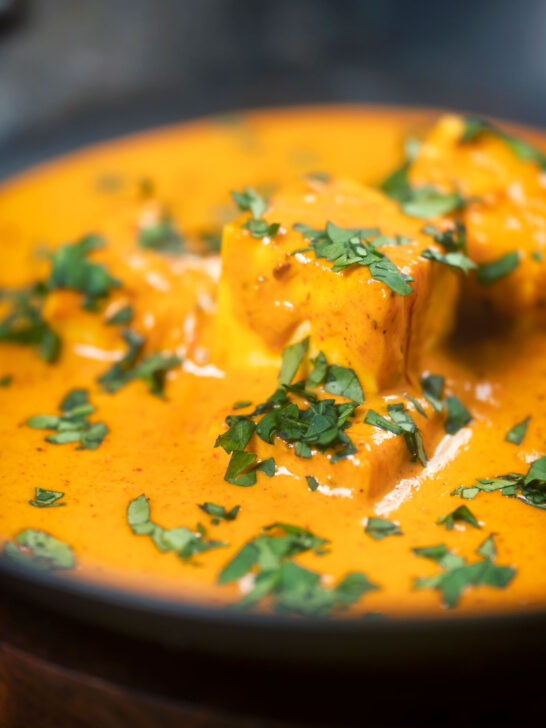 Close-up Indian shahi paneer curry in a creamy sauce served with fresh coriander.