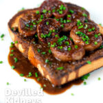 Classic British devilled lambs kidneys on toast with snipped chives featuring a title overlay.