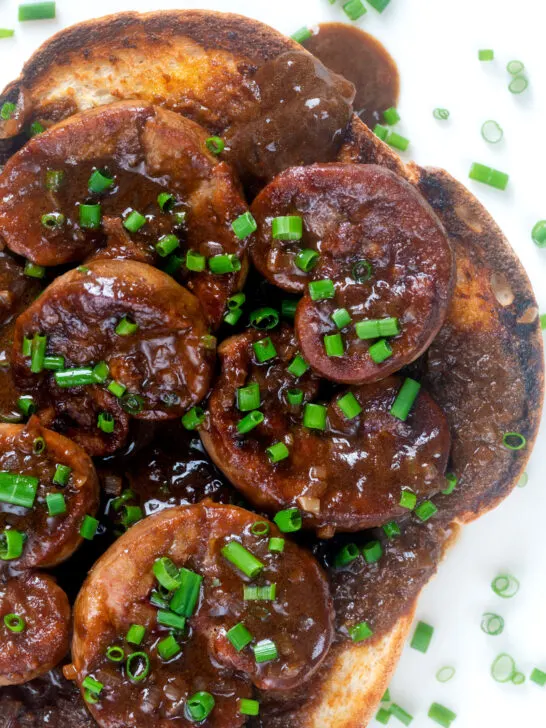 Close up overhead classic British devilled lambs kidneys on toast with snipped chives.