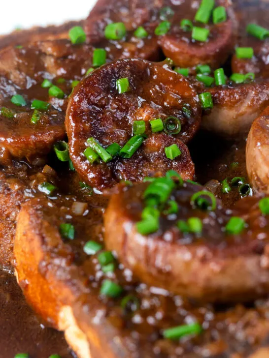 Close up classic British devilled lambs kidneys on toast with snipped chives.