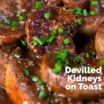 Close up classic British devilled lambs kidneys on toast with snipped chives featuring a title overlay.