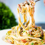 Creamy ham and mushroom tagliatelle with a creme fraiche and mustard sauce on a fork.