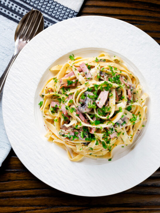 Overhead creamy ham and mushroom tagliatelle with a creme fraiche and mustard sauce.