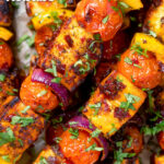 Overhead close-up harissa halloumi and vegetable kebab skewers featuring a title overlay.