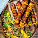 Overhead harissa halloumi and vegetable kebabs served with a spicy mango salad.