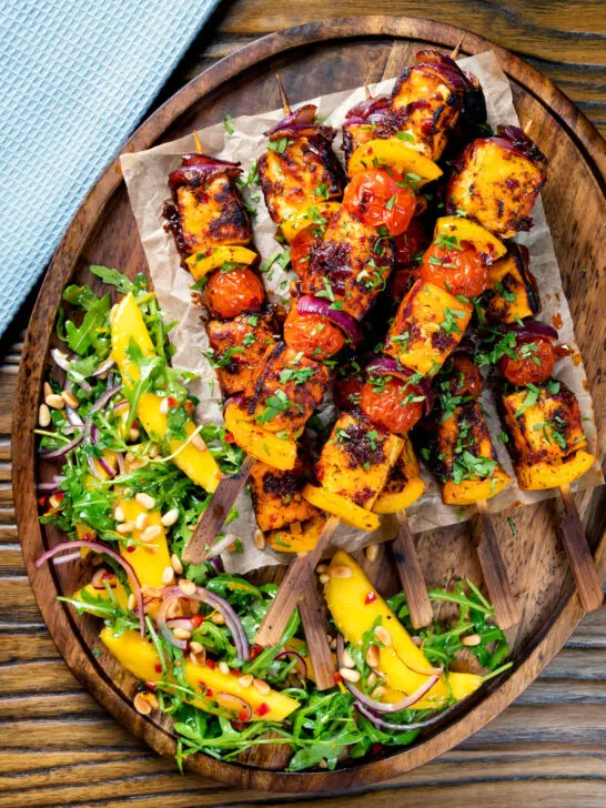 Overhead harissa halloumi and vegetable kebabs served with a spicy mango salad.