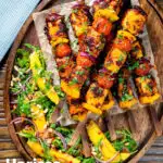 Over head harissa halloumi and vegetable kebabs served with a spicy mango salad featuring a title overlay.