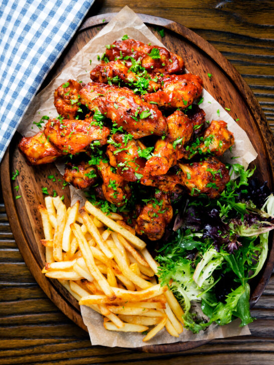 Overhead sticky date and harissa chicken wings served with French fries and salad.