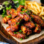 Sticky date and harissa chicken wings served with French fries and salad.