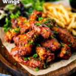 Sticky date and harissa chicken wings served with French fries and salad featuring a title overlay.